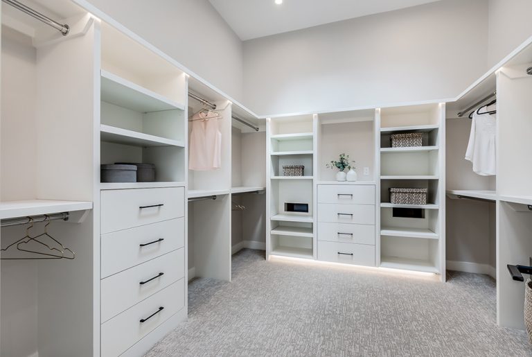 Spacious walk-in closet with white cabinetry, shelving units, drawers, and clothing rods throughout