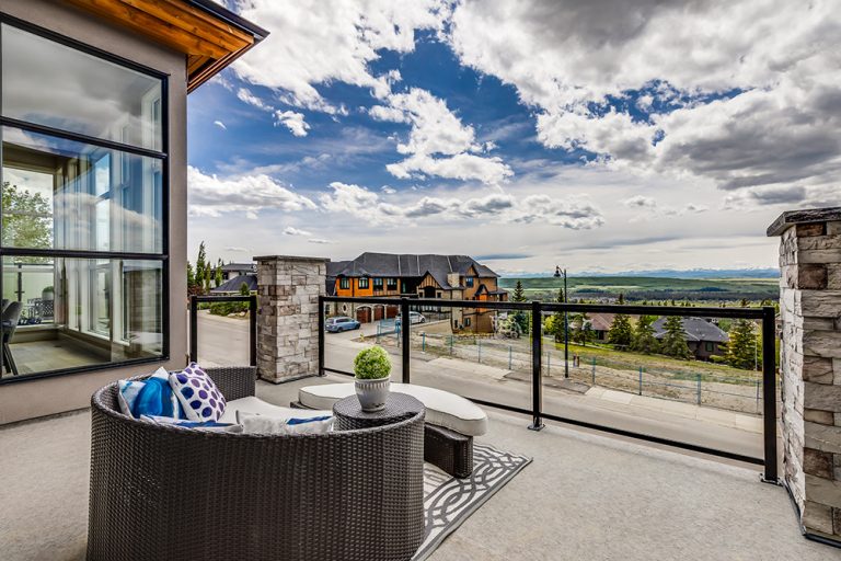 Modern rooftop patio with seating area overlooking suburban neighborhood and mountains under blue sky with clouds