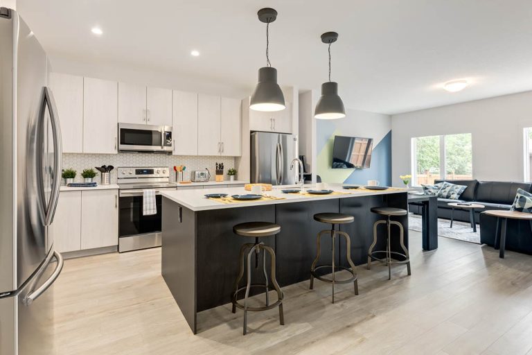 Modern kitchen with black island, white cabinetry, stainless steel appliances, and pendant lighting